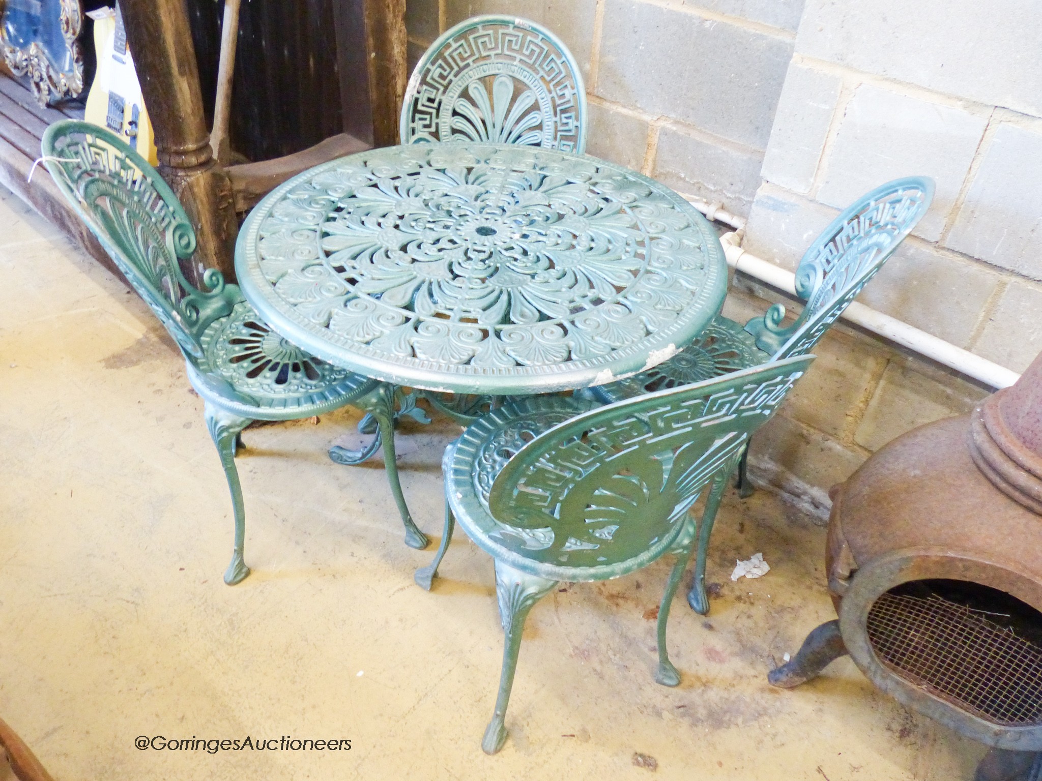 A Victorian style circular aluminium garden table, diameter 80cm, together with four matching garden chairs